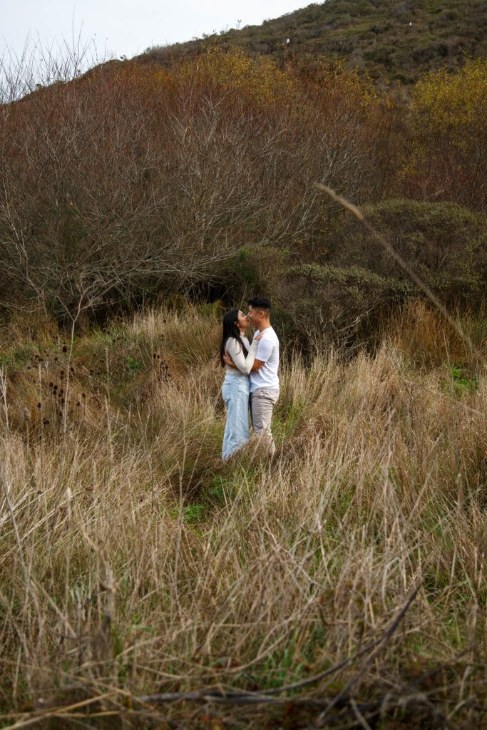 Couple kissing in the grassy fields in Marin Ca