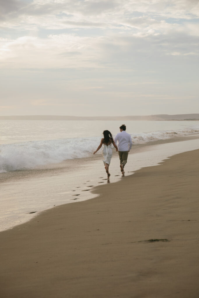engaged couple running on the beach. 
