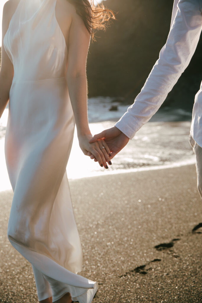 couple holding hands at black sands beach