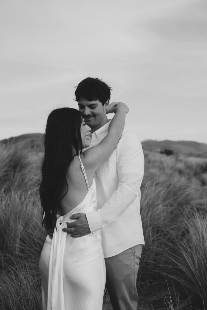 Couple embracing in the dunes at Point Reyes, black and white engagement photography Bay Area
