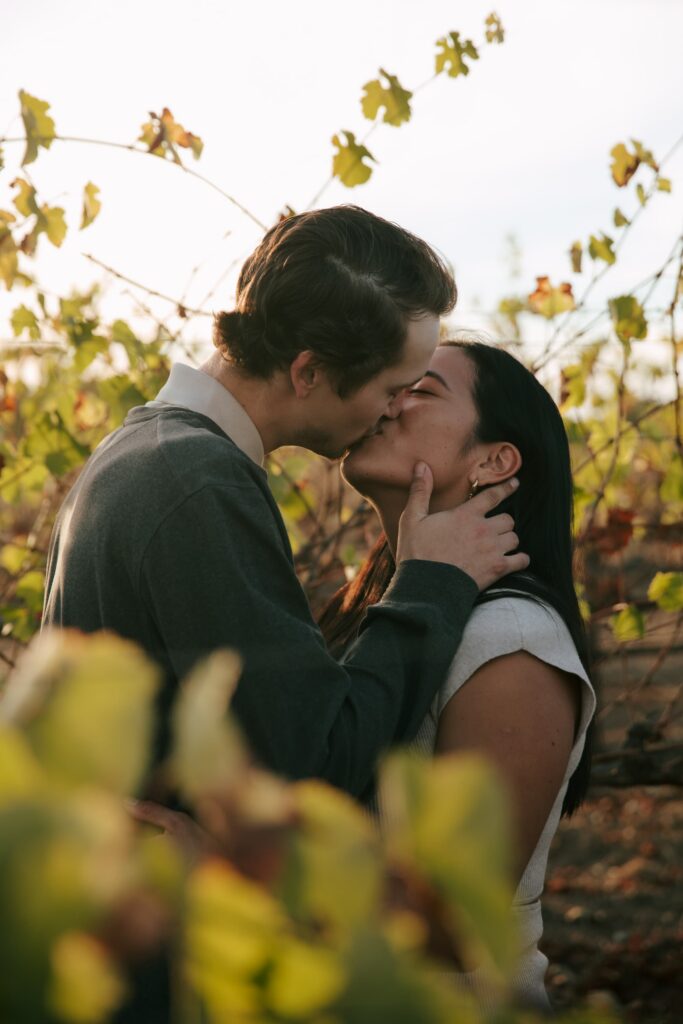 Couple kissing among golden flowers in Napa Valley vineyard, Bay Area engagement photographer Rose Freedman