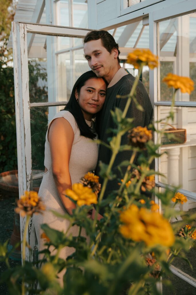 Engaged couple in Napa Valley greenhouse surrounded by marigolds, California engagement photography