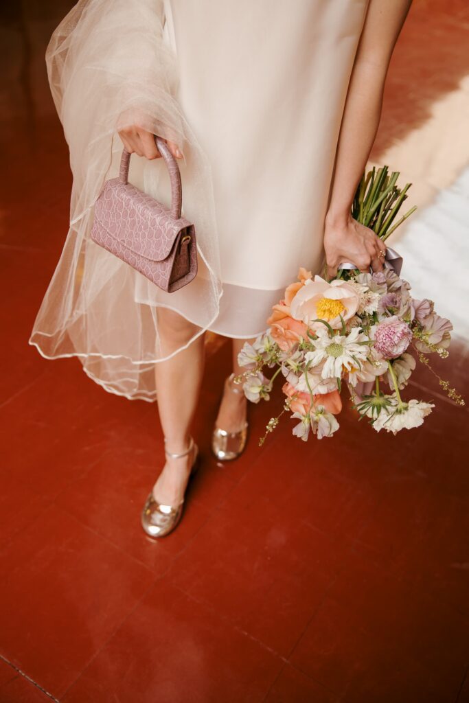 Close-up of bride holding lavender clutch and wildflower bouquet in silver heels, Marin Civic Center wedding
