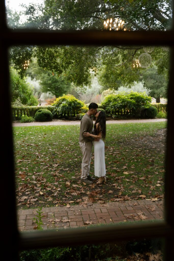 Couple kissing framed through window at Filoli Estate gardens, Bay Area engagement photographer Rose Freedman