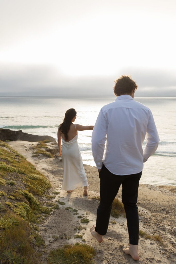 Couple walking along Half Moon Bay bluffs at sunset, Bay Area engagement photographer Rose Freedman