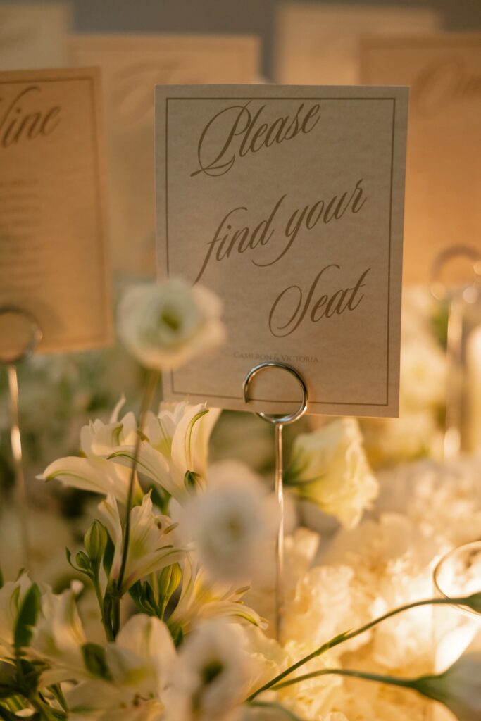 Elegant wedding seating sign surrounded by white lily florals at Meritage Resort Napa cave reception