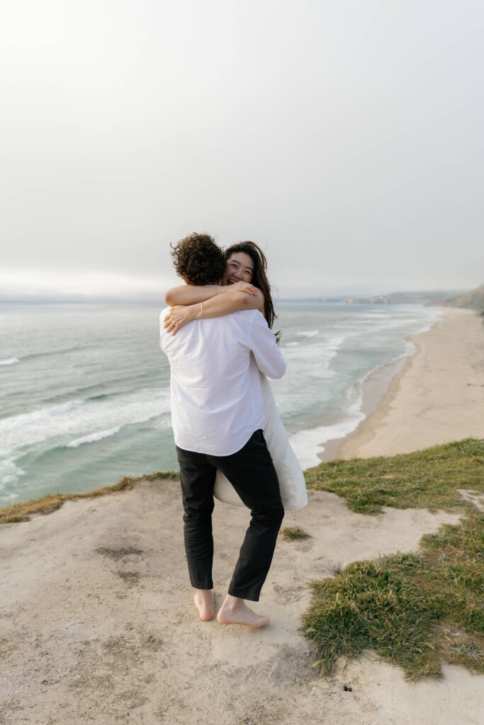 Couple embracing on Half Moon Bay coastal bluffs, Bay Area engagement photographer