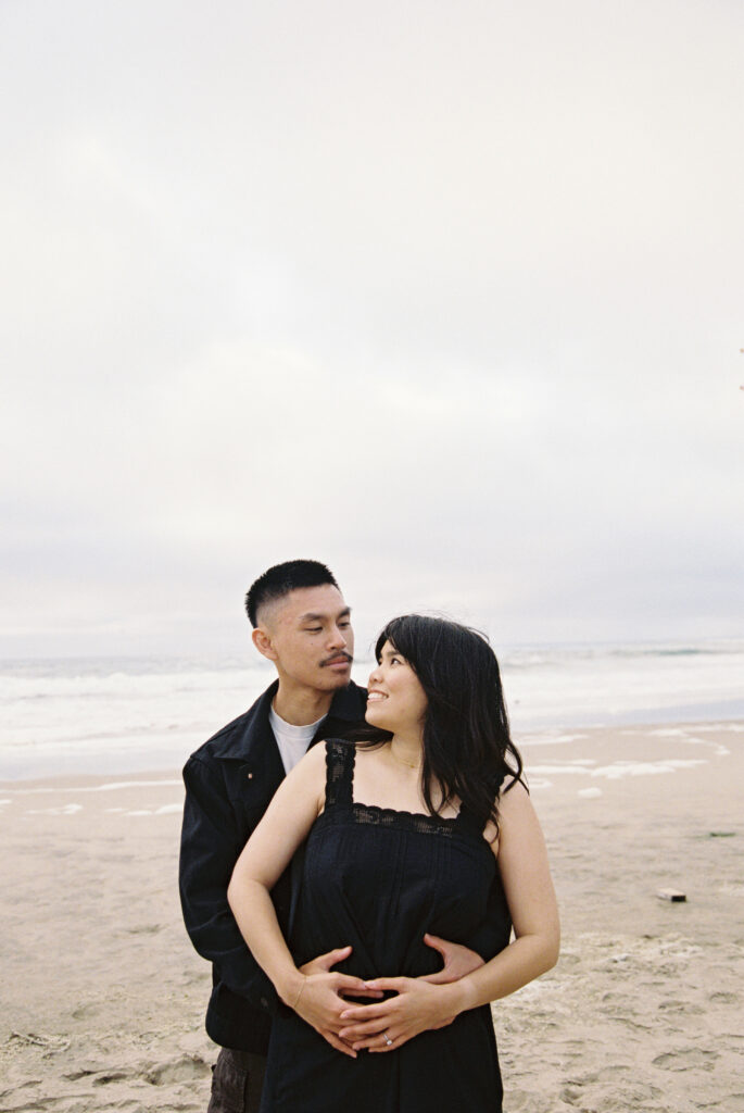 Couple embracing on Half Moon Bay beach on 35mm film, Bay Area couples photographer Rose Freedman
