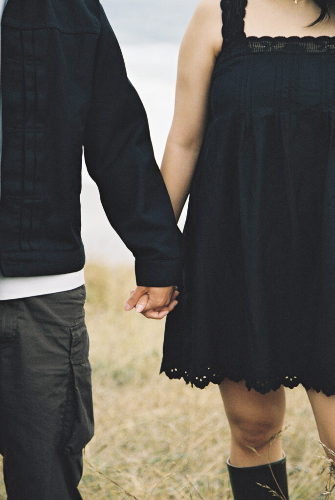 Couple holding hands close-up at Half Moon Bay on 35mm film, Bay Area couples photographer Rose Freedman