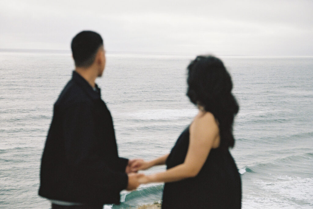 Couple holding hands looking at ocean at Half Moon Bay on 35mm film, Rose Freedman Photography