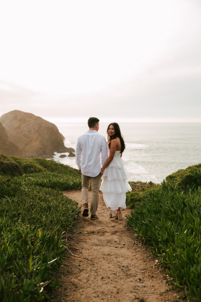 Couple on Marin Headlands cliff overlooking ocean at Rodeo Beach engagement session, Bay Area engagement photographer Rose Freedman