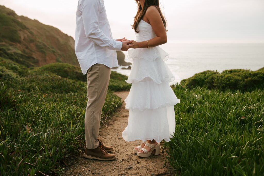 Couple holding hands on coastal cliff path at Rodeo Beach engagement session, Bay Area engagement photographer Rose Freedman