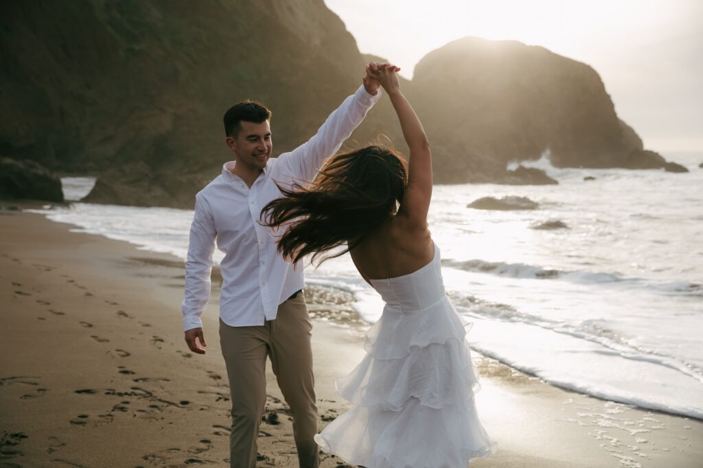 Couple twirling on Rodeo Beach at golden hour, Bay Area engagement photographer Rose Freedman