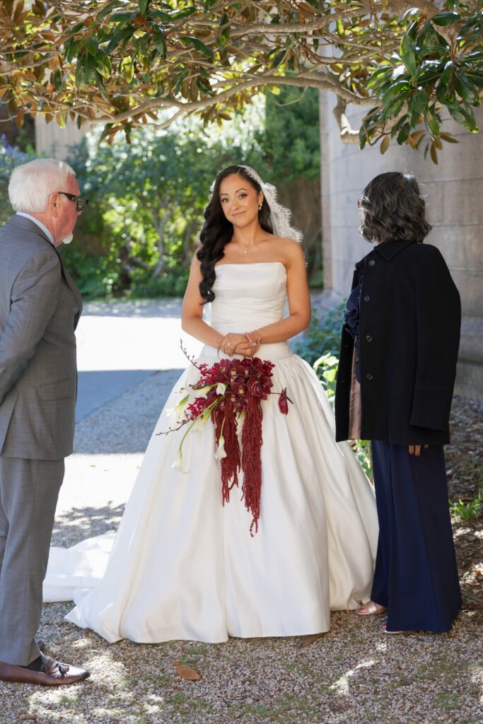 Bride holding burgundy cascading bouquet with family at Palace of Fine Arts San Francisco, San Francisco wedding photographer Rose Freedman