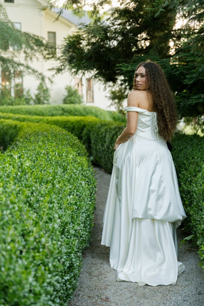 Bride looking back over shoulder in boxwood garden path at Park Winters, Park Winters wedding photographer Rose Freedman
