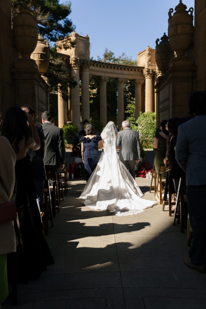 Bride walking down aisle at Palace of Fine Arts wedding ceremony with cathedral train, San Francisco wedding photographer Rose Freedman