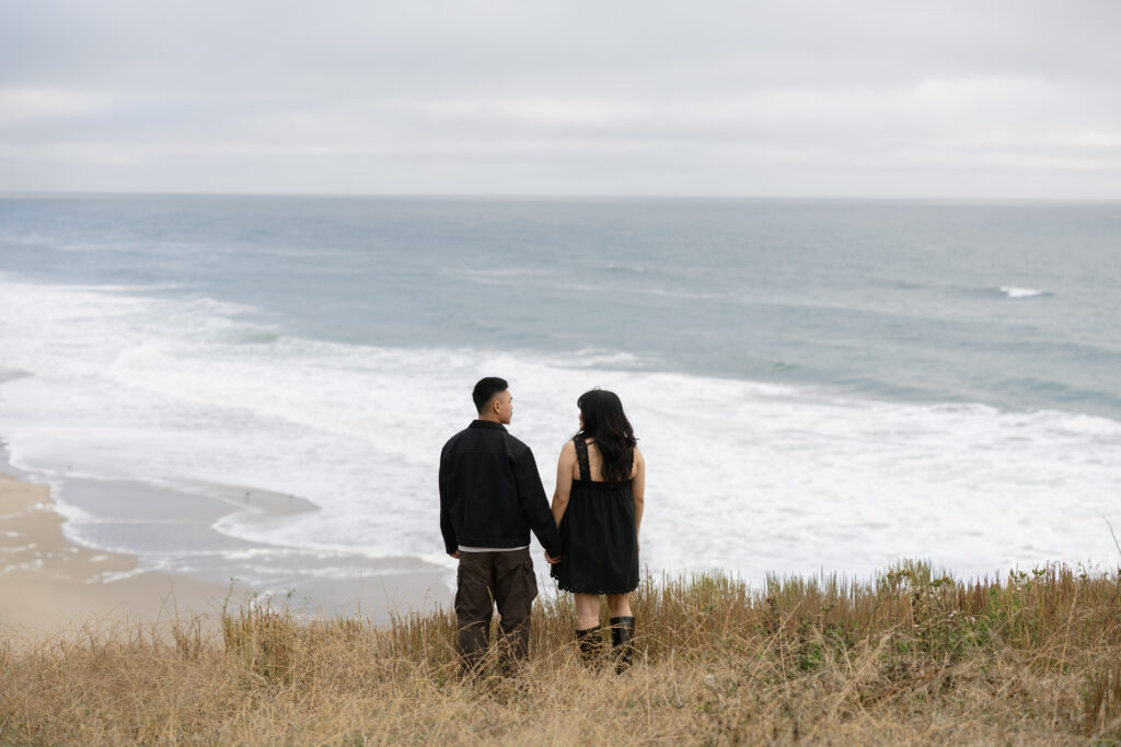 Couple holding hands looking at ocean at Half Moon Bay, Bay Area couples photographer Rose Freedman