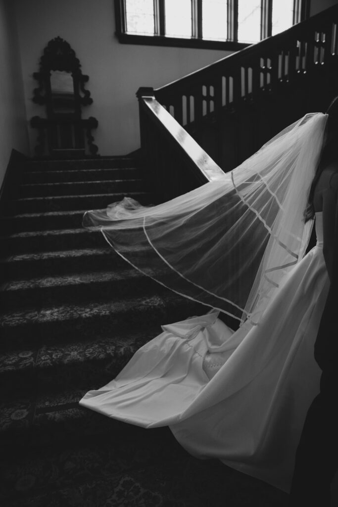 Wedding veil trailing across dark wood staircase at Kohl Mansion, Bay Area wedding photographer Rose Freedman