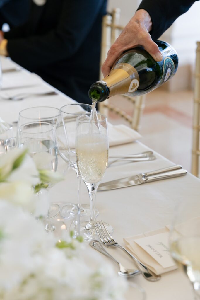 Champagne being poured at Flood Mansion wedding reception table, San Francisco wedding photographer Rose Freedman