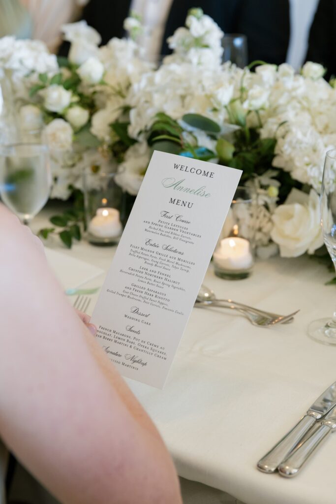 Personalized wedding menu card with white rose centerpiece and candles at Flood Mansion reception, Rose Freedman Photography