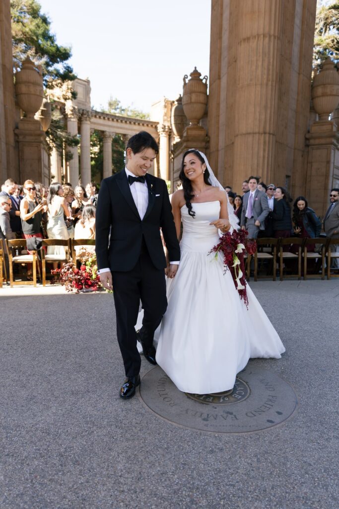Bride and groom recessional at Palace of Fine Arts wedding with guests celebrating, San Francisco wedding photographer Rose Freedman
