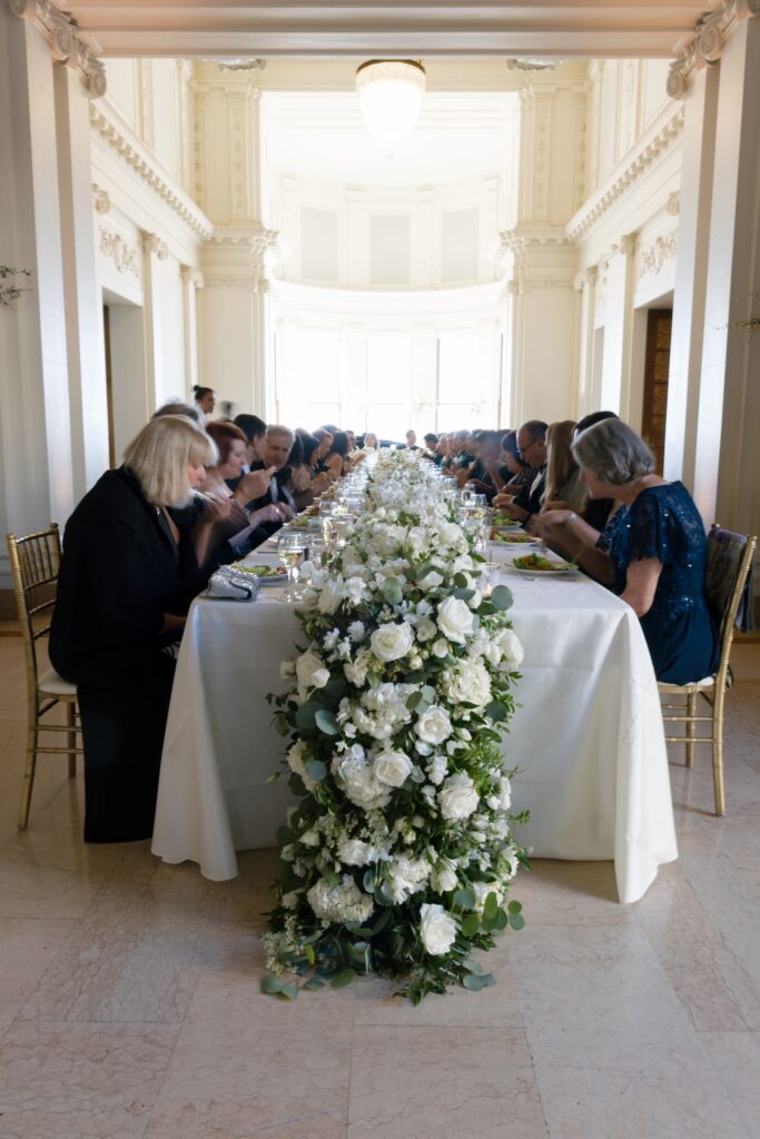 Long reception dinner table with white rose garland at Flood Mansion San Francisco, Bay Area wedding photographer Rose Freedman