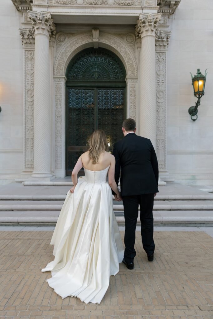 Bride and groom walking into Flood Mansion ornate entrance, San Francisco wedding photographer Rose Freedman