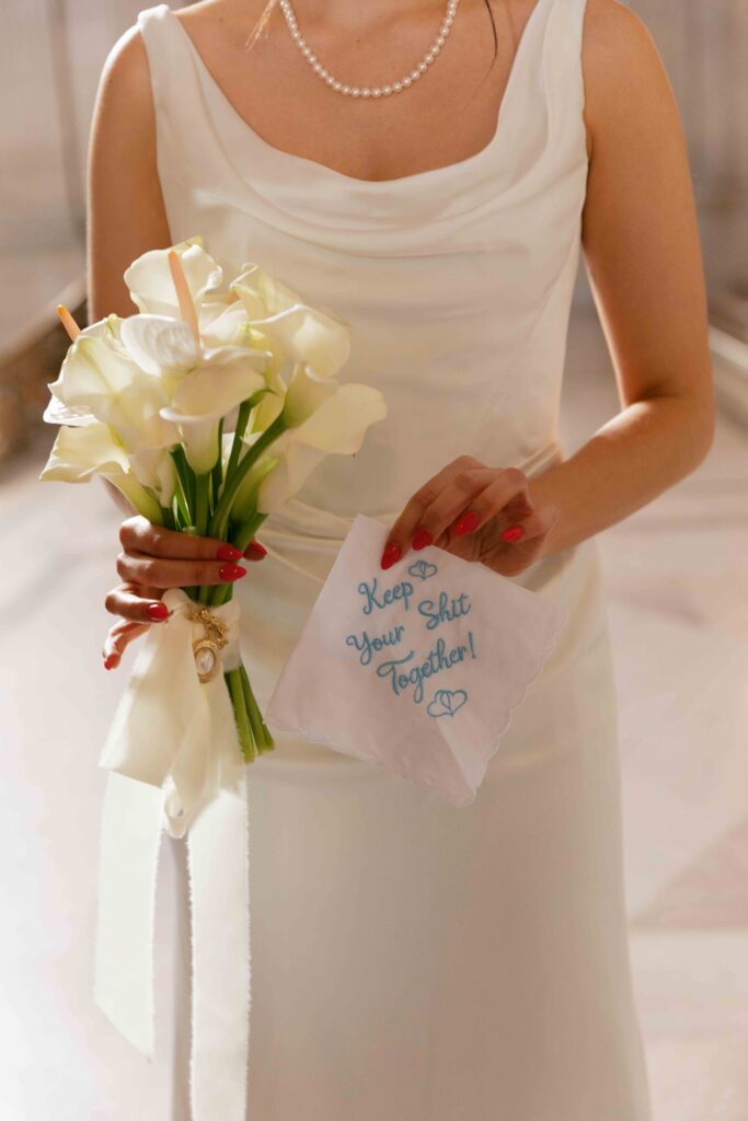 Bride holding white calla lily bouquet and embroidered handkerchief at SF City Hall wedding, Rose Freedman Photography