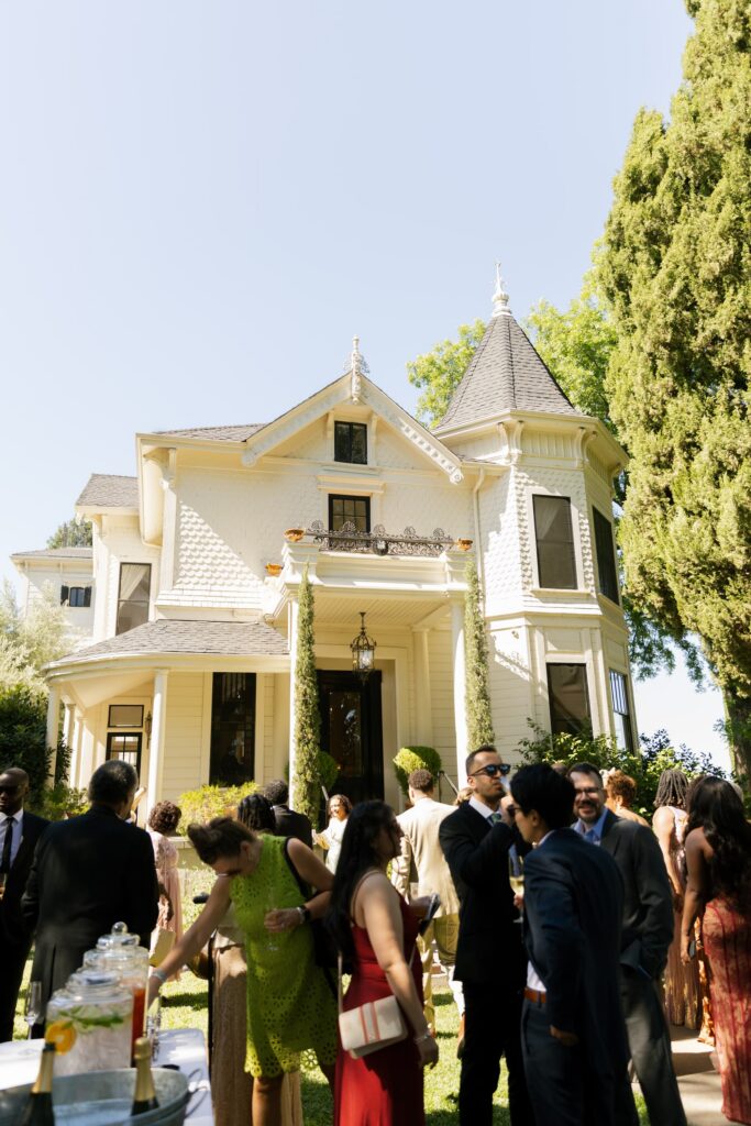 Guests mingling at cocktail hour in front of Park Winters Victorian house, Park Winters wedding photographer Rose Freedman