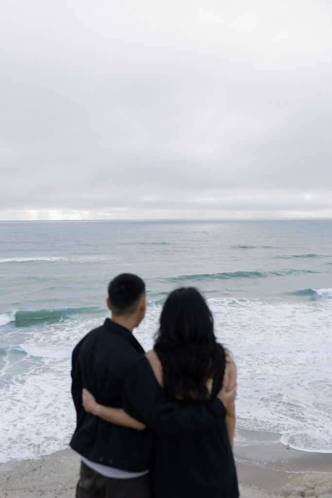 Couple watching waves at Half Moon Bay from behind, Bay Area couples photographer Rose Freedman