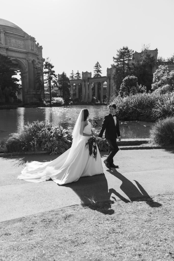 Bride and groom walking at Palace of Fine Arts lagoon in black and white, San Francisco wedding photographer Rose Freedman