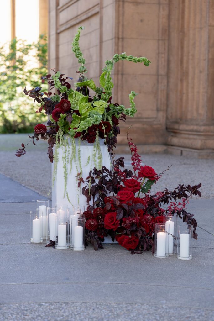 Dramatic burgundy floral installation with candles at Palace of Fine Arts wedding ceremony, San Francisco wedding photographer Rose Freedman