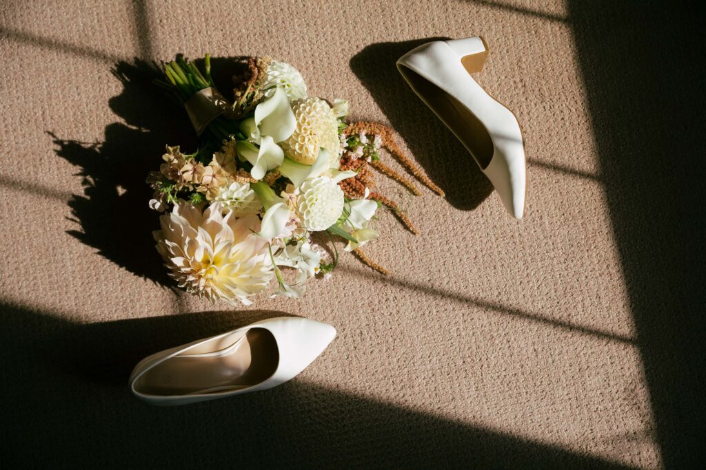 Bride's white dahlia bouquet and heels with window light shadows at Kohl Mansion wedding, Bay Area wedding photographer Rose Freedman