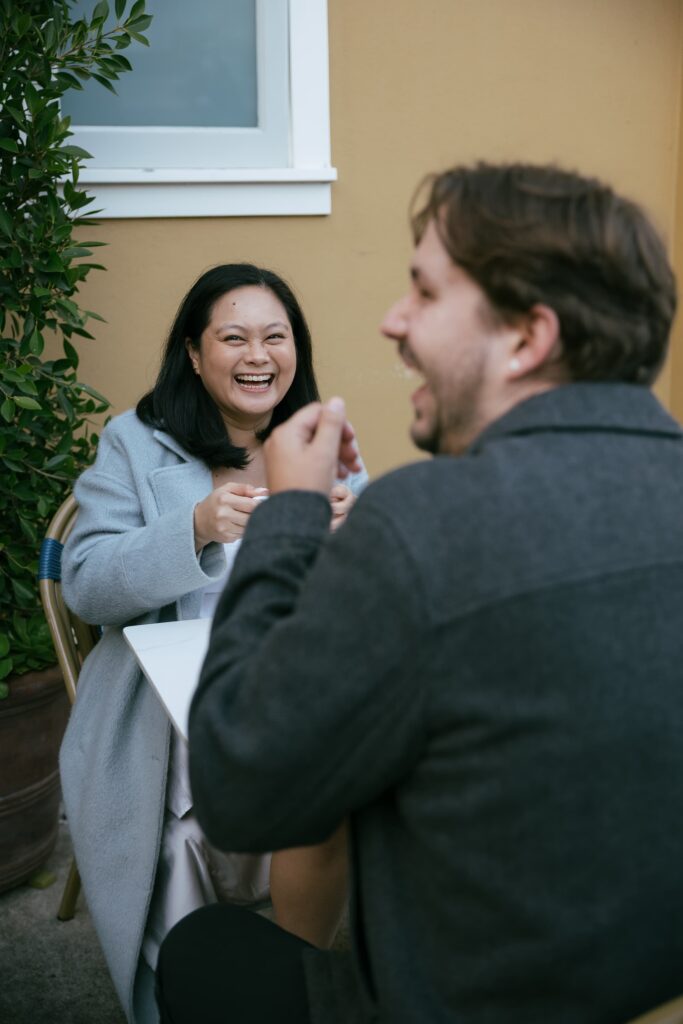 Couple laughing at cafe during San Francisco engagement session, Bay Area engagement photographer Rose Freedman