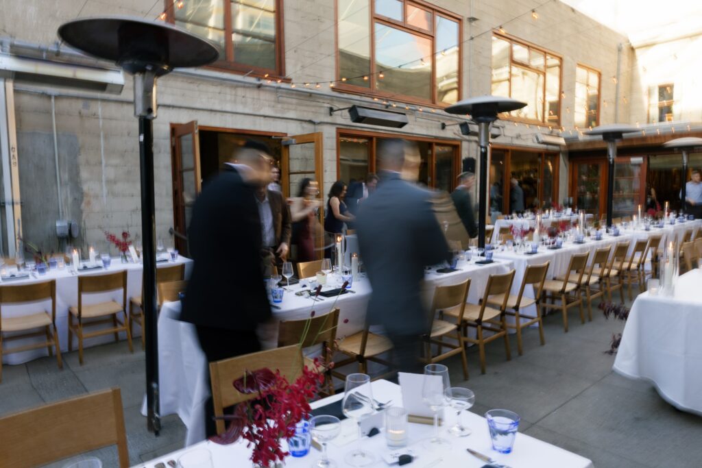 Wedding guests moving through Foreign Cinema courtyard reception, San Francisco wedding photographer Rose Freedman