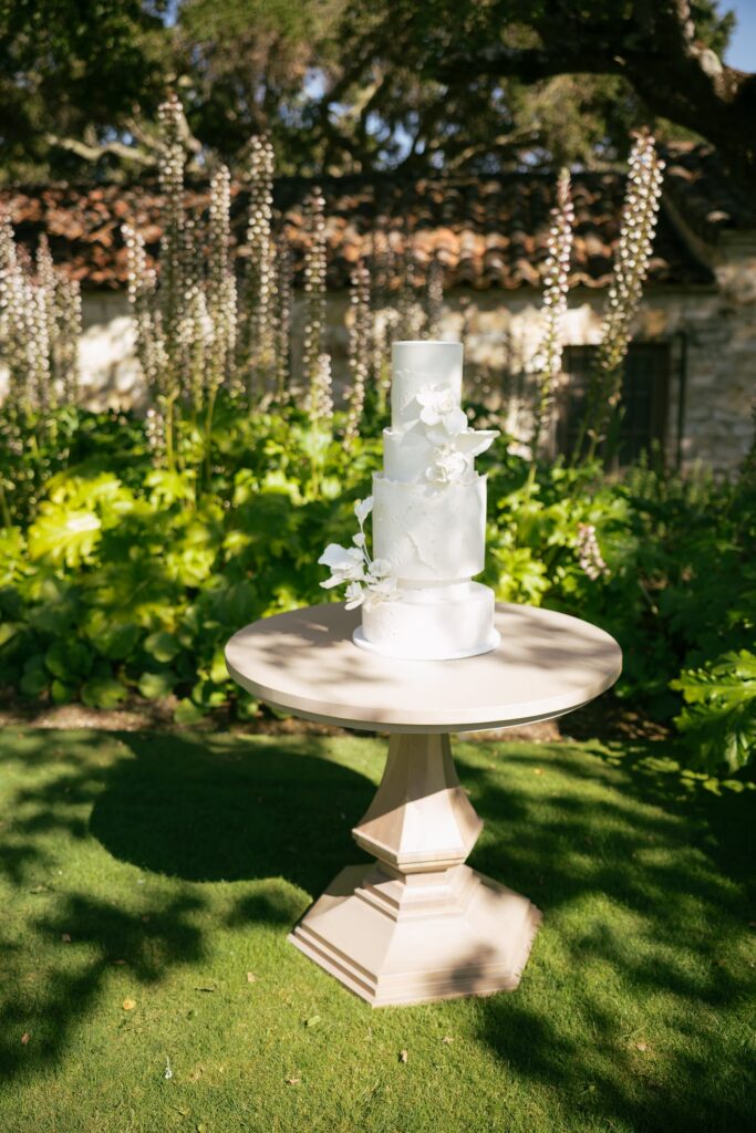 Three-tier white wedding cake with sugar flowers in Holman Ranch garden, Carmel Valley wedding photographer Rose Freedman