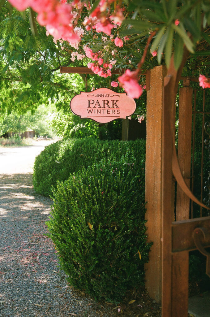 Inn at Park Winters sign with pink flowering trees, Park Winters wedding venue photographer Rose Freedman