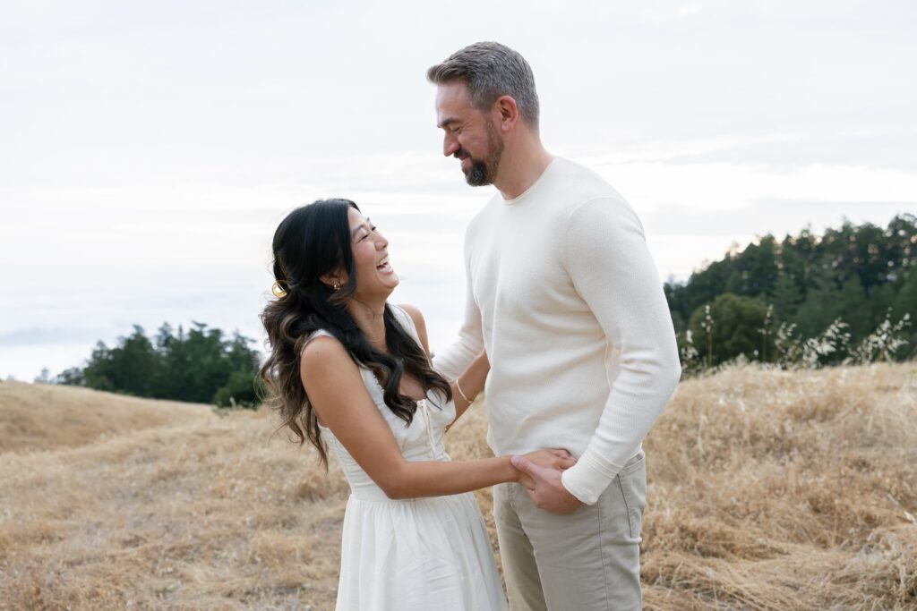Couple laughing together in golden field at Mount Tamalpais engagement session, Bay Area engagement photographer Rose Freedman