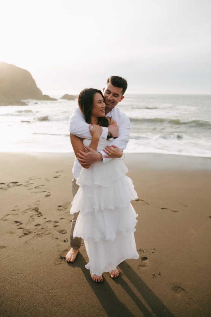 Couple embracing on California coastline, beach engagement session Rose Freedman Photography
