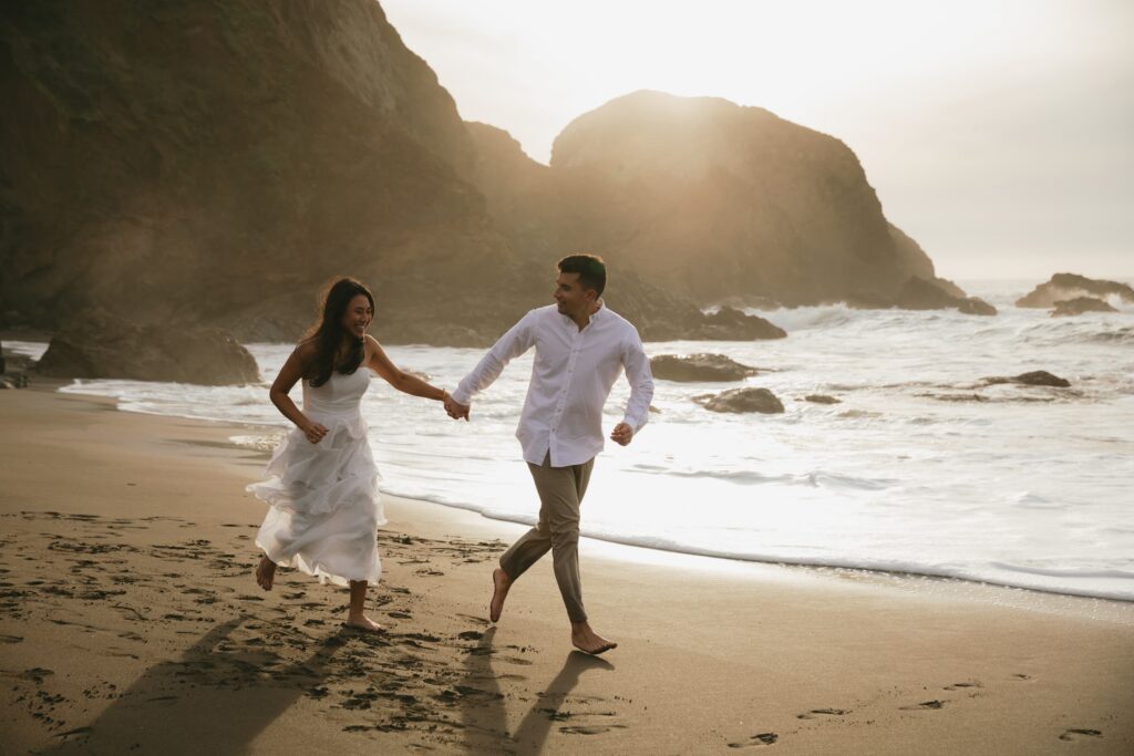 Couple running on California coastline, beach engagement session Rose Freedman Photography