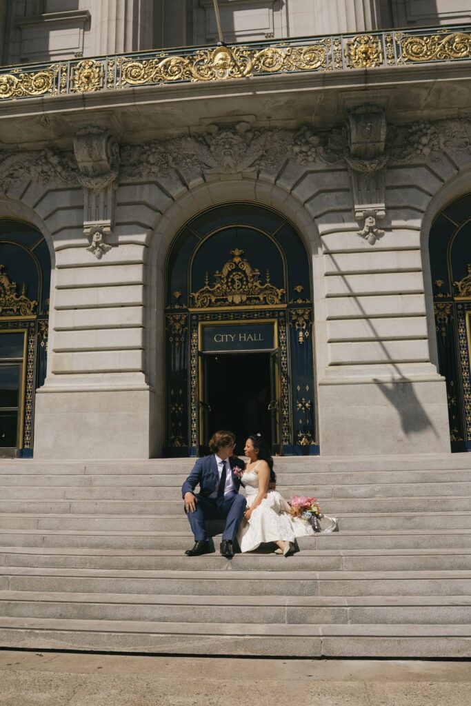 Couple sitting on San Francisco City Hall exterior steps, SF elopement photographer Rose Freedman