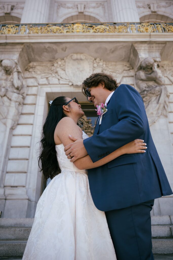 Couple embracing outside San Francisco City Hall front entrance, film photography elopement Rose Freedman