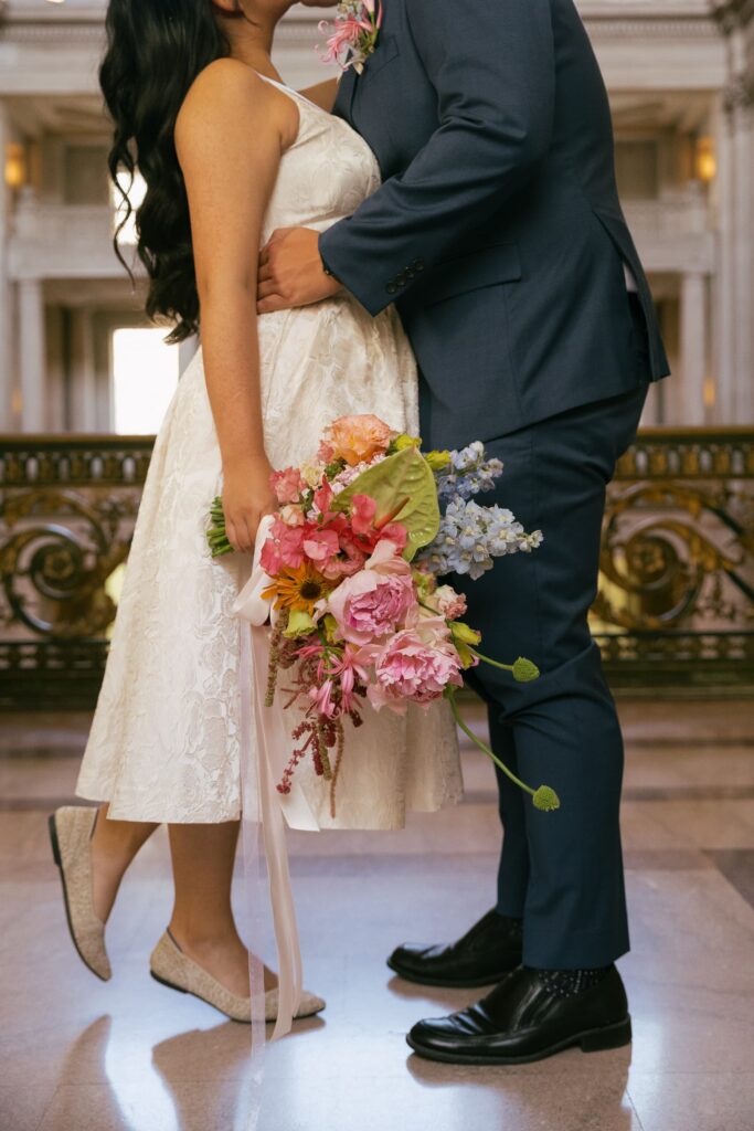 Bride with colorful bouquet at San Francisco City Hall rotunda balcony, elopement photographer Rose Freedman