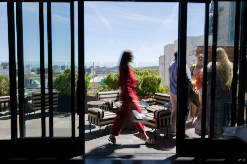 Guest in red dress walking on Charmaine's Rooftop San Francisco, event photographer Rose Freedman